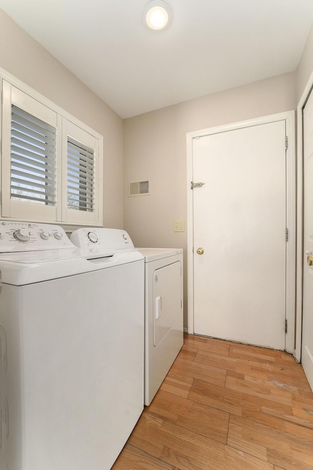 laundry area featuring washing machine and dryer and light wood-type flooring