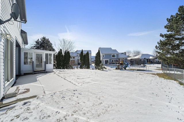 snowy yard with a trampoline and a sunroom