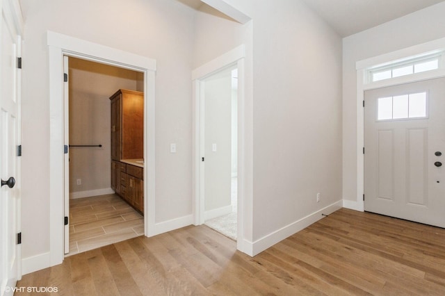 foyer entrance featuring light wood finished floors and baseboards