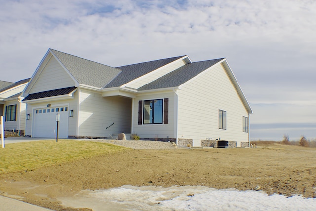 view of front of home featuring a garage, metal roof, roof with shingles, a standing seam roof, and central AC