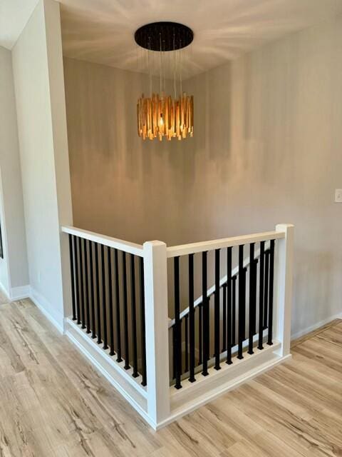 stairway with hardwood / wood-style flooring and a notable chandelier