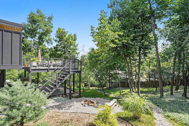 view of yard featuring a deck, a fire pit, fence, and stairway