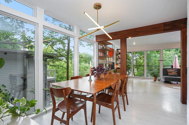 dining area with light wood-type flooring, an inviting chandelier, and plenty of natural light