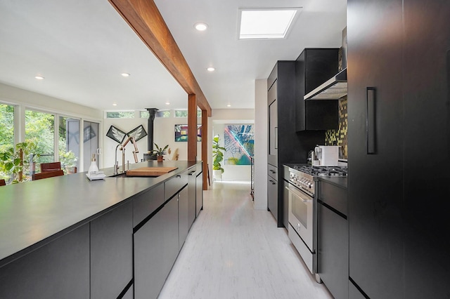 kitchen with stainless steel stove, dark cabinetry, fridge, dark countertops, and modern cabinets