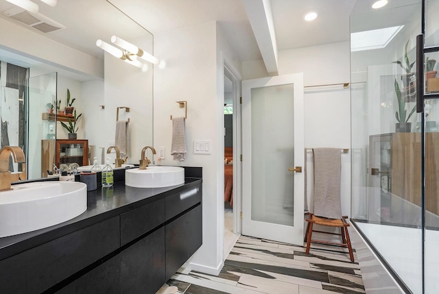 bathroom featuring double vanity, a stall shower, visible vents, and a sink