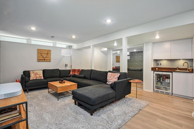 living room with beverage cooler, light wood-style floors, recessed lighting, and wet bar