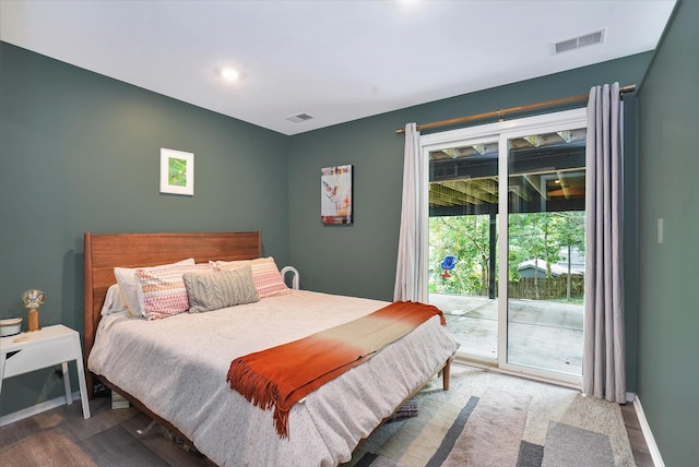 bedroom featuring baseboards, wood finished floors, visible vents, and access to exterior