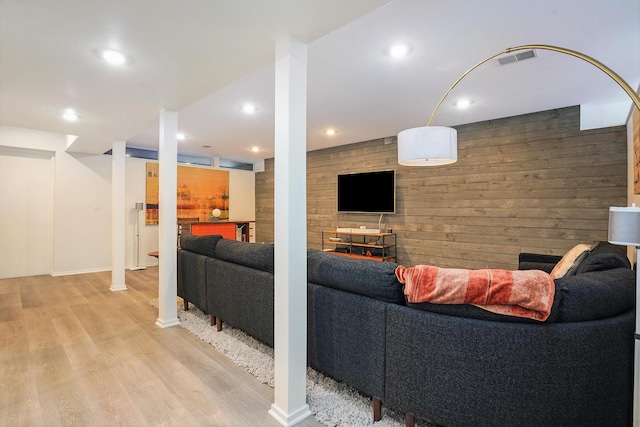 living area with wood walls, recessed lighting, visible vents, and light wood-style floors