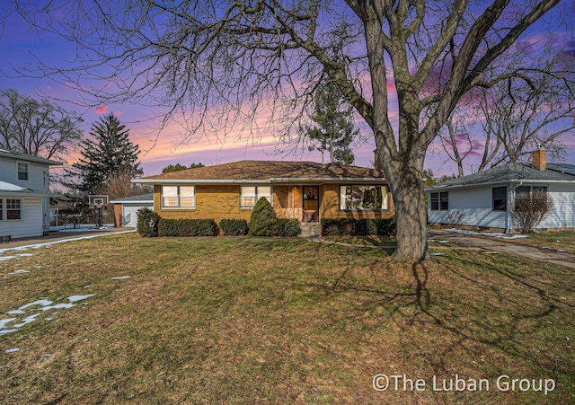 ranch-style home featuring a garage and a lawn