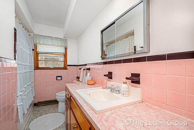 bathroom with tile patterned flooring, vanity, tile walls, and toilet