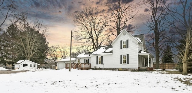 snow covered rear of property featuring a garage