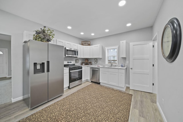 kitchen featuring white cabinetry, sink, light hardwood / wood-style floors, and appliances with stainless steel finishes