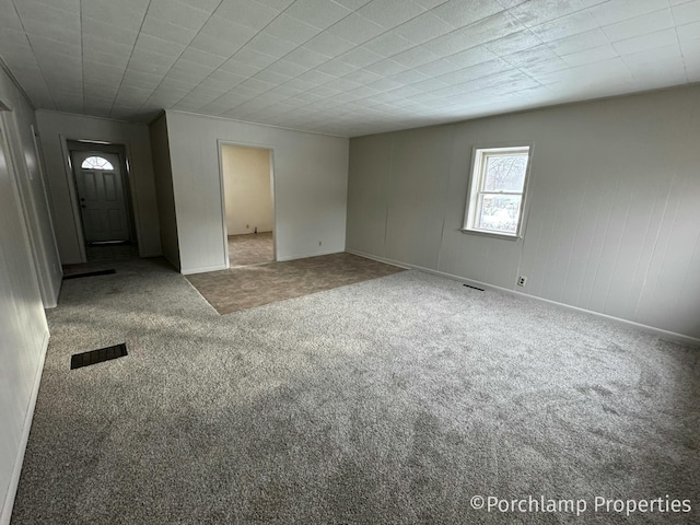 unfurnished room with carpet floors, visible vents, and baseboards