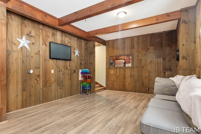 living area with light wood finished floors, wooden walls, visible vents, and beamed ceiling