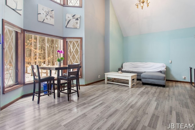 dining space with high vaulted ceiling, light wood-style flooring, and baseboards