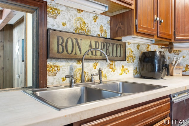 details featuring brown cabinets, light countertops, decorative backsplash, a sink, and wallpapered walls