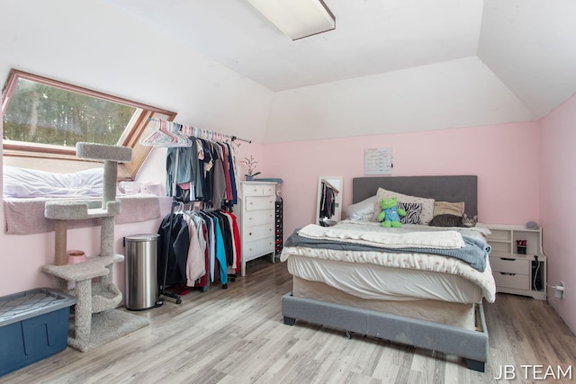 bedroom with lofted ceiling and light wood-style flooring