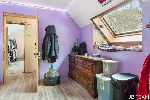 bedroom featuring light wood finished floors and lofted ceiling with skylight