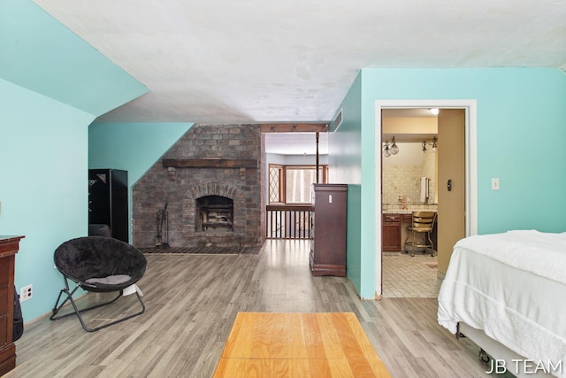 bedroom with a fireplace and light wood-style flooring