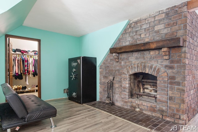 living area featuring lofted ceiling, a fireplace, and wood finished floors