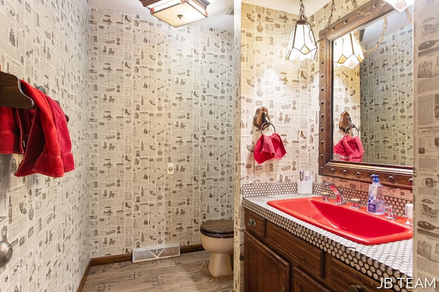 bathroom with toilet, visible vents, wood finished floors, and vanity