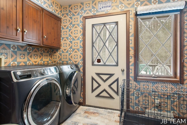 laundry room with cabinet space, wallpapered walls, and independent washer and dryer