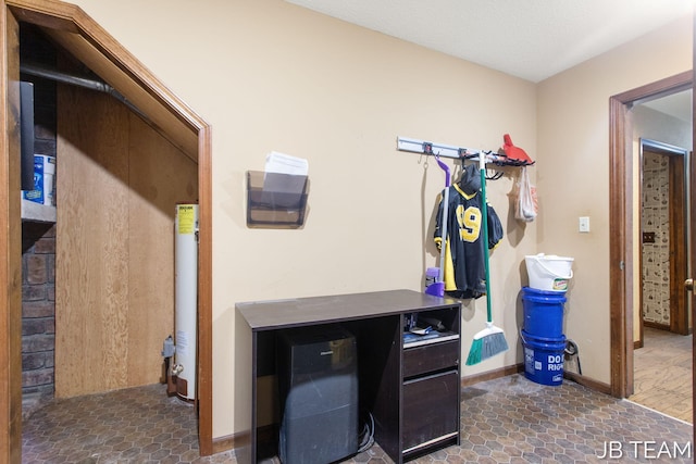 laundry room with stone finish flooring, water heater, and baseboards