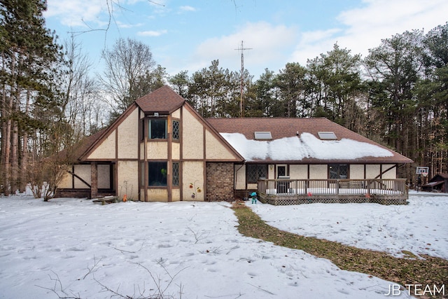 snow covered back of property featuring a deck and stucco siding