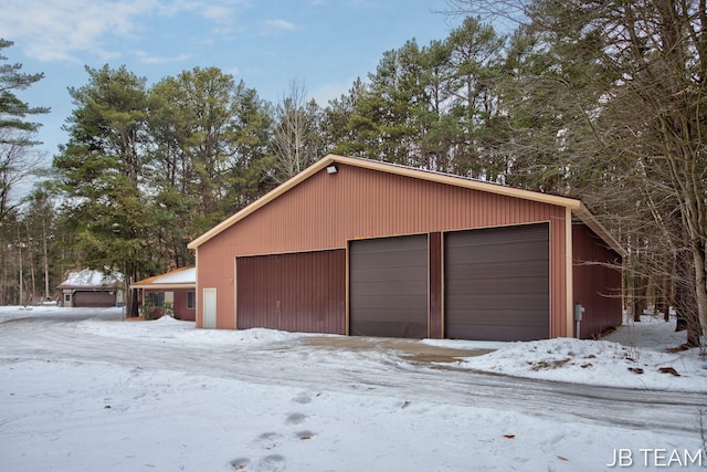 snow covered garage with a detached garage