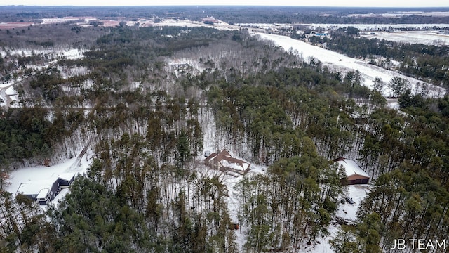 snowy aerial view with a wooded view