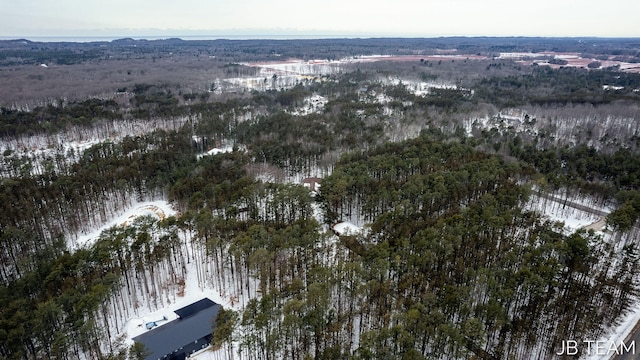 snowy aerial view featuring a wooded view