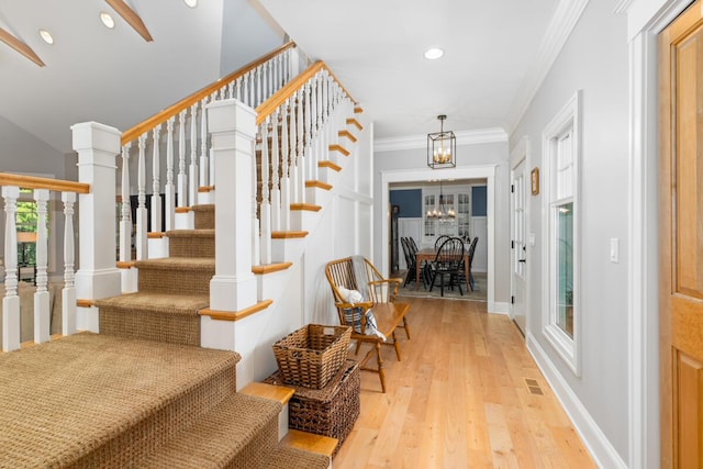 stairway featuring an inviting chandelier, ornamental molding, and wood-type flooring