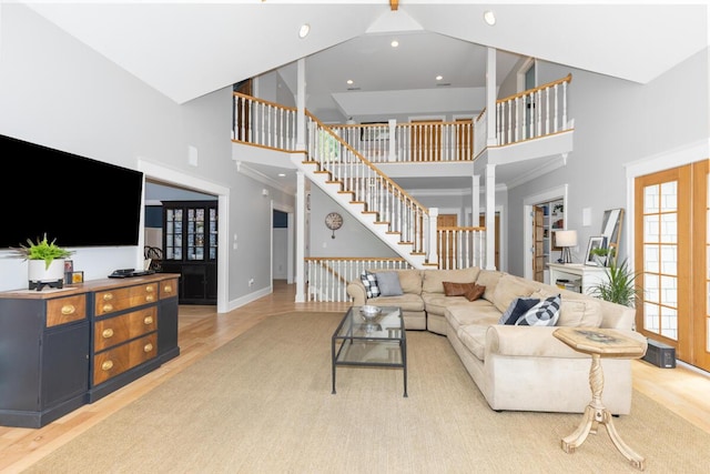 living room featuring light wood-type flooring, decorative columns, and a high ceiling