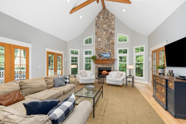 living room with beam ceiling, high vaulted ceiling, a stone fireplace, french doors, and light wood-type flooring