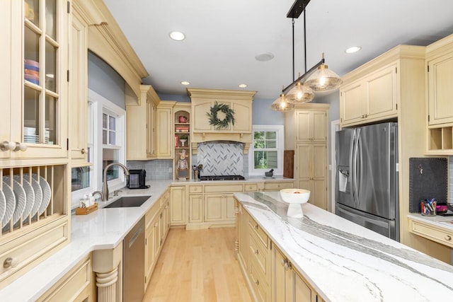 kitchen featuring sink, stainless steel appliances, light stone counters, decorative backsplash, and decorative light fixtures