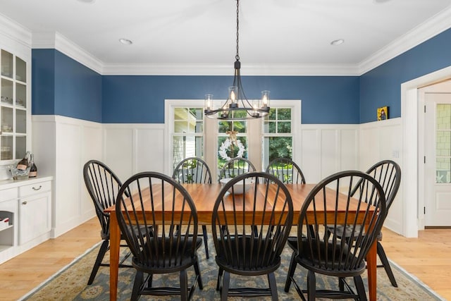 dining area featuring an inviting chandelier, ornamental molding, and light wood-type flooring