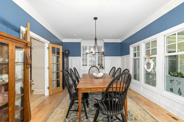 dining space with an inviting chandelier, crown molding, and light hardwood / wood-style floors