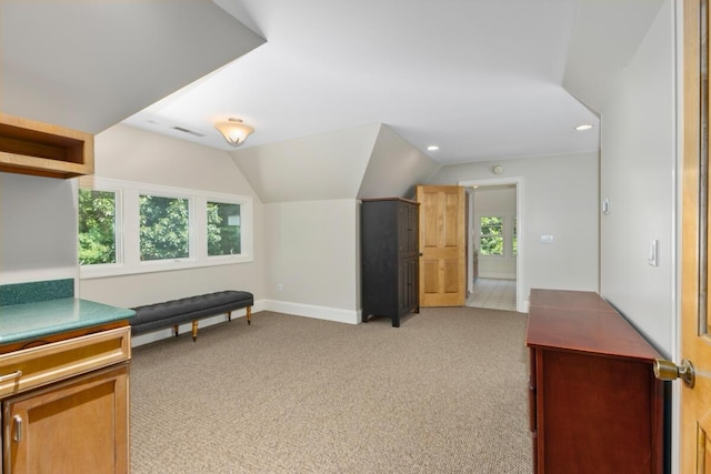 interior space with vaulted ceiling and light colored carpet