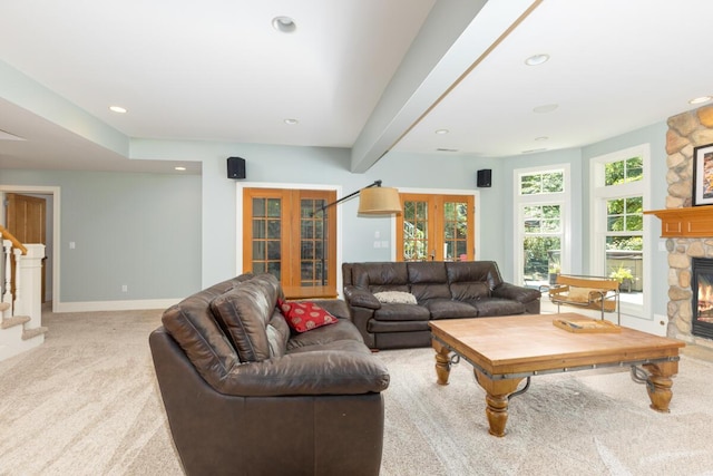 living room with beamed ceiling, light colored carpet, a fireplace, and french doors