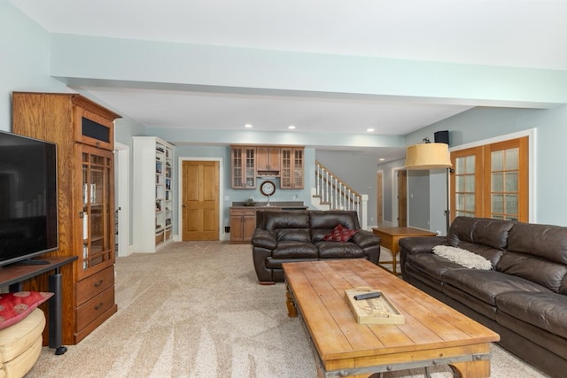 living room featuring light colored carpet, beam ceiling, and french doors