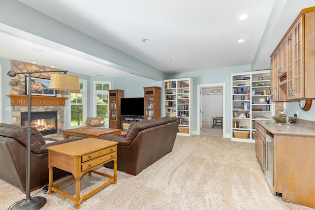 living room with a stone fireplace, sink, and light carpet