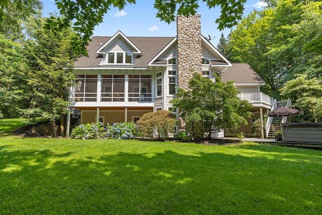 rear view of property featuring a yard, a sunroom, and a hot tub