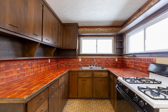 kitchen with decorative backsplash, sink, white range with gas stovetop, and a textured ceiling