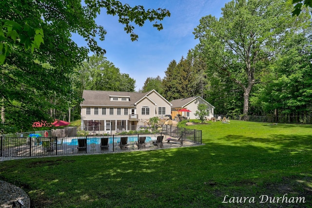 rear view of property featuring a yard, fence, and a fenced in pool