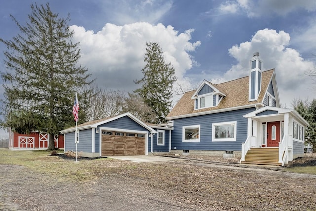 view of front of house featuring a shingled roof, an outbuilding, driveway, and an attached garage