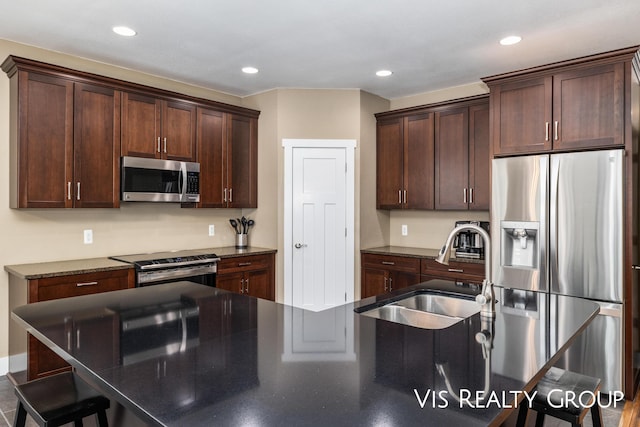 9340 Freedom Dr, West Olive, MI 49460 - kitchen featuring a breakfast bar area, appliances with stainless steel finishes, a sink, and dark brown cabinets