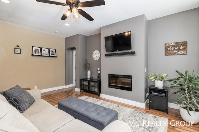 9340 Freedom Dr, West Olive, MI 49460 - living area with arched walkways, wood finished floors, ceiling fan, and baseboards