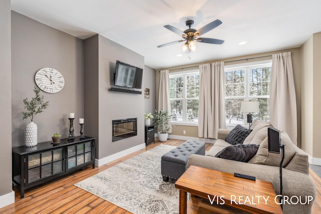 9340 Freedom Dr, West Olive, MI 49460 - living room with baseboards, a ceiling fan, a glass covered fireplace, and wood finished floors
