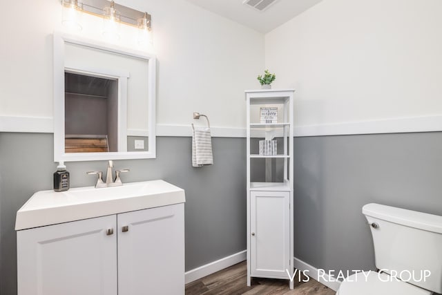 9340 Freedom Dr, West Olive, MI 49460 - half bathroom featuring vanity, baseboards, toilet, visible vents, and wood finished floors
