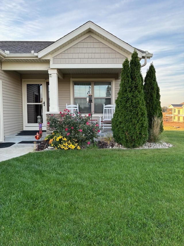 exterior space with covered porch, a front lawn, and a shingled roof